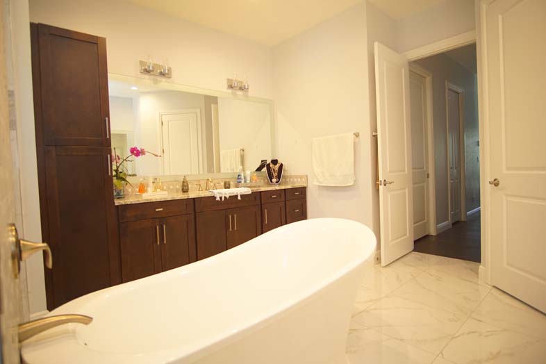 White bathtub and brown cabinets in bathroom built by SPEC Development